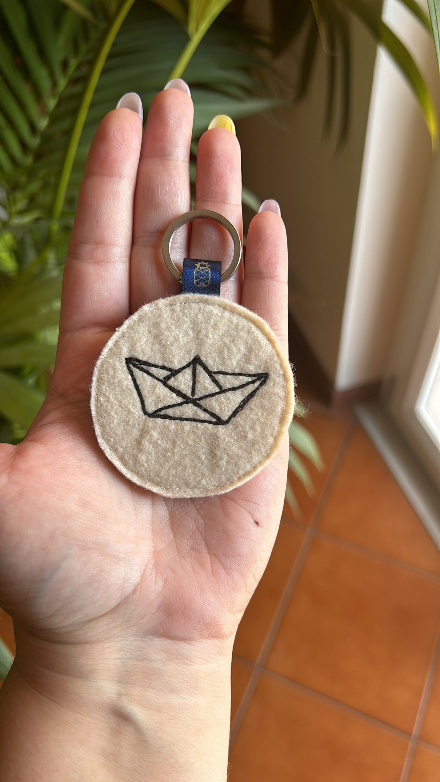 Portachiavi fatto a mano in feltro chiaro con ricamata una barchetta di carta