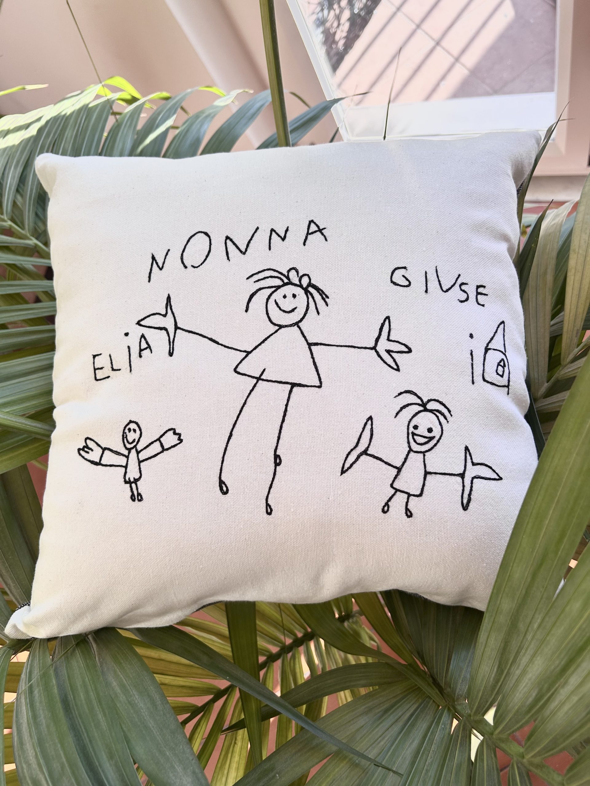 Cuscino fatto a mano in cotone bianco con ricamato un disegno fatto da un bambino con la sua famiglia