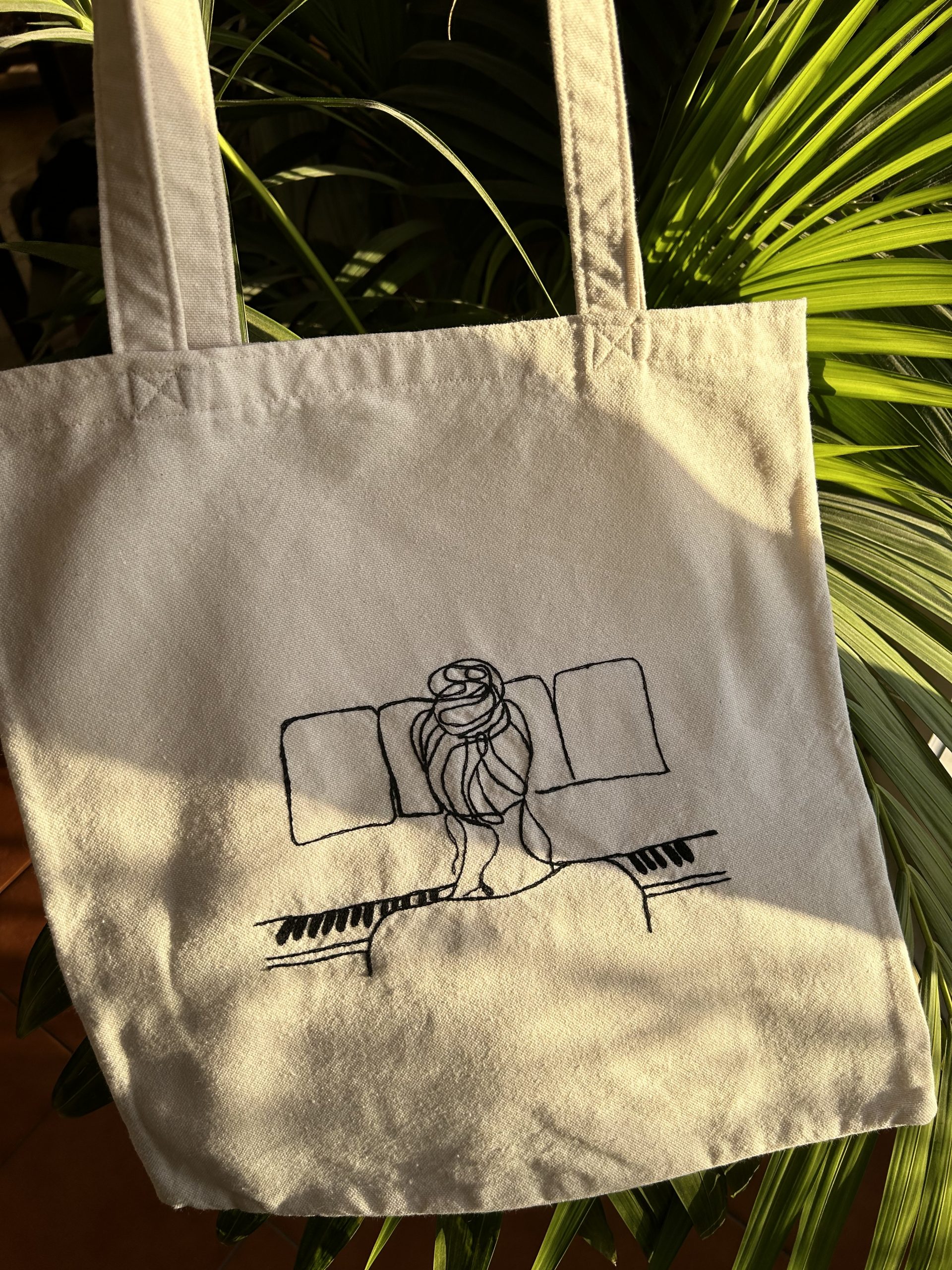 Borsa tote fatta a mano in cotone bianco con ricamata una figura di donna che suona il piano